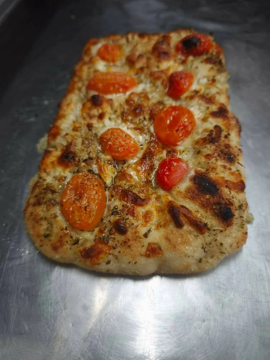 Pinsa allongée aux tomates cerises et herbes, cuite au feu de bois